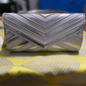 Silver and white clutch bag. No strap. One pocket inside with light blue lining.